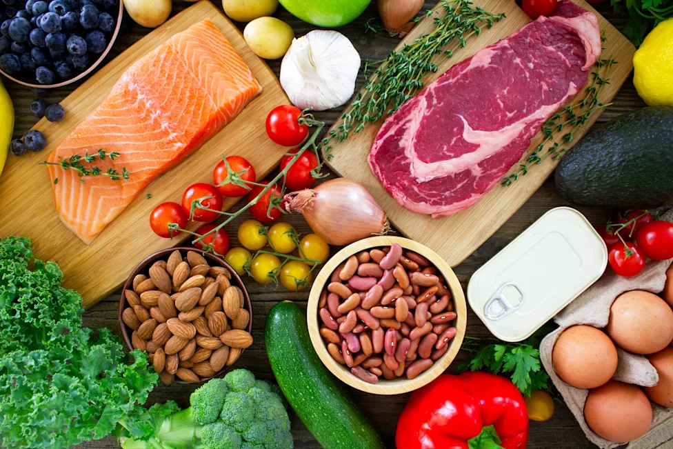 Fresh salmon, beef, eggs, vegetables and pulses laid out on a table
