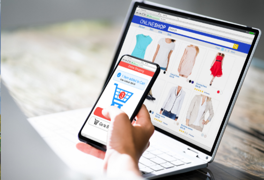 Person shopping for clothes online on a phone and laptop